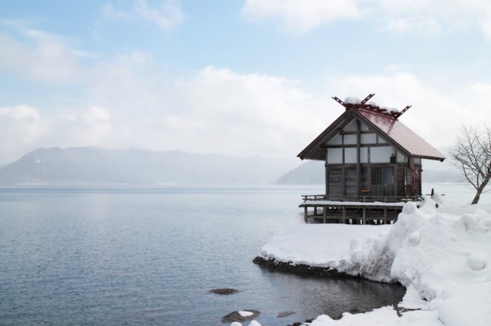 Traditional Japanese House in winter while it's snowing next to a lake