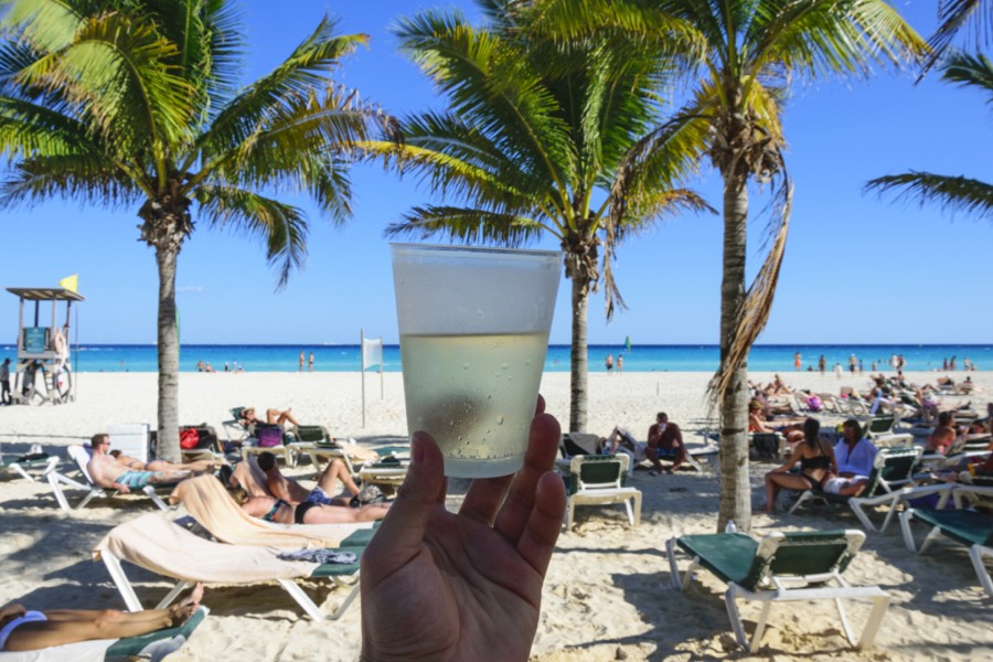 An alcoholic drink held by hand in front of Tokyo beach