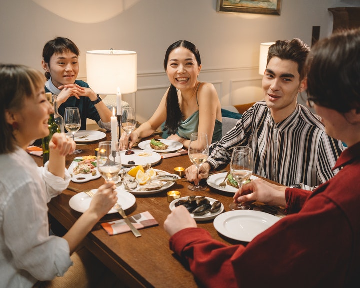A group of friends having dinner while talking about Japanese tongue twisters