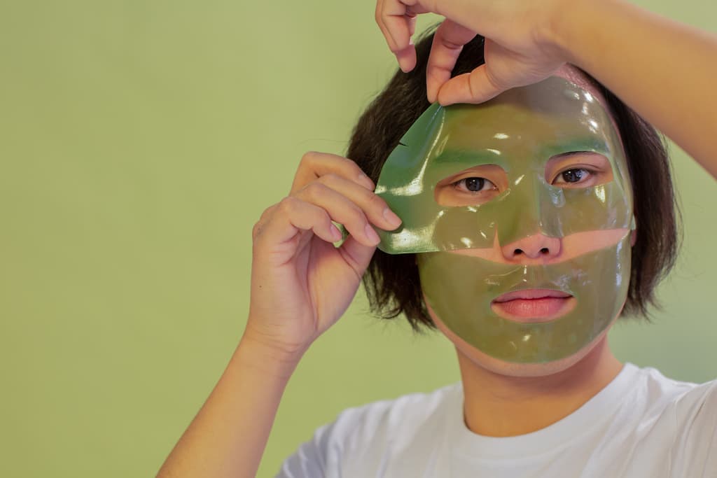 An asian man applying the top half of a 2 part face mask as an alternative step in the japanese skincare process