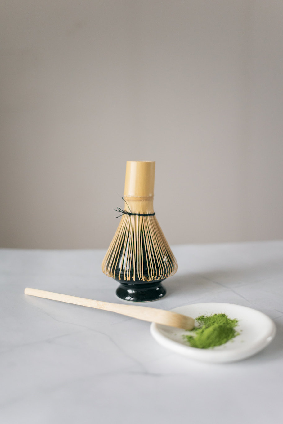 Japanese matcha tea on a plate with a chasaku (Japanese tea scoop) and chasen (tea whisk)