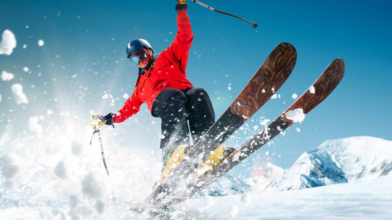 A person skiing while kicking up a lot of snow as they make a small jump
