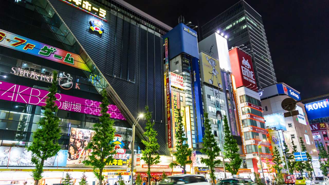 Pink sign with the words - AKB48 Cafe in Akihabara - surrounded by other stores such as a game centre and manga and anime goods store