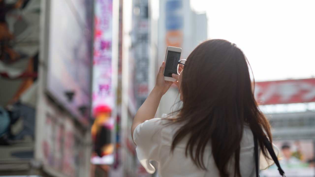 Girl holding her phone up and taking pictures of Akihabara