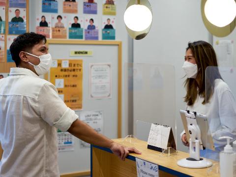 Japanese language school reception area - student leaning on the counter and having a conversation with a smiling receptionist