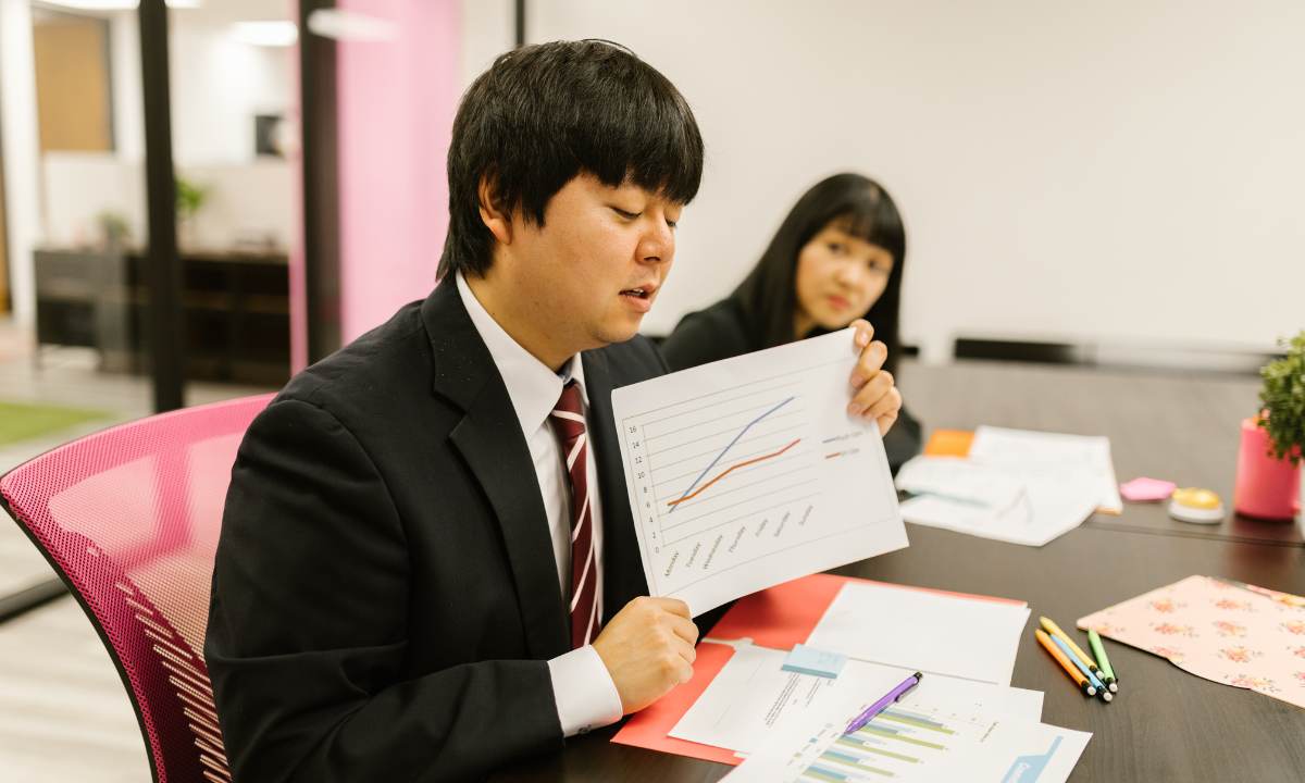 Buisnessman presenting a pitch at a meeting with a poster showing a graph that is going up