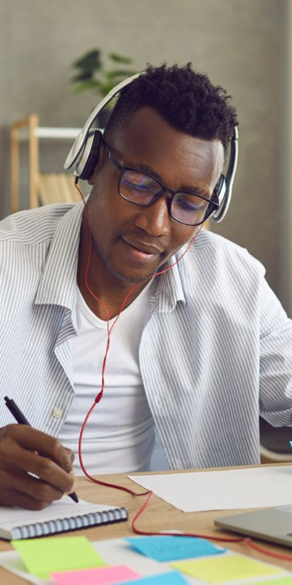 African male using headphones and using laptop to learn Japanese
