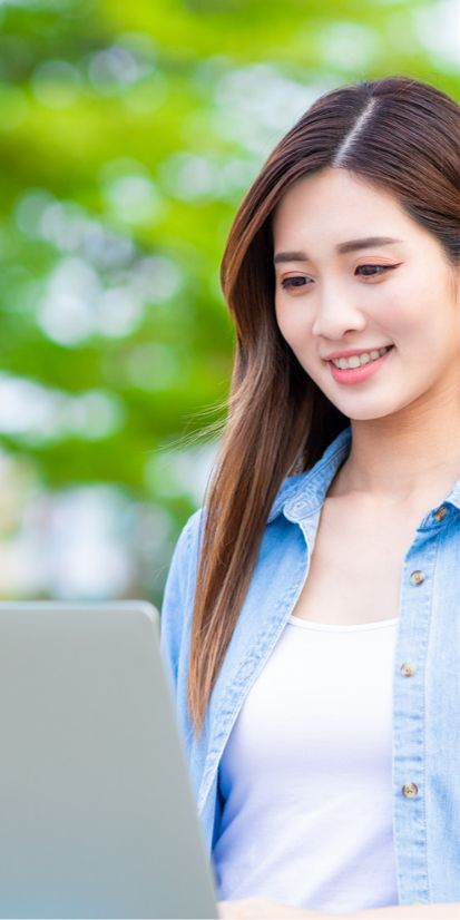 Asian female outside using a laptop to study Japanese