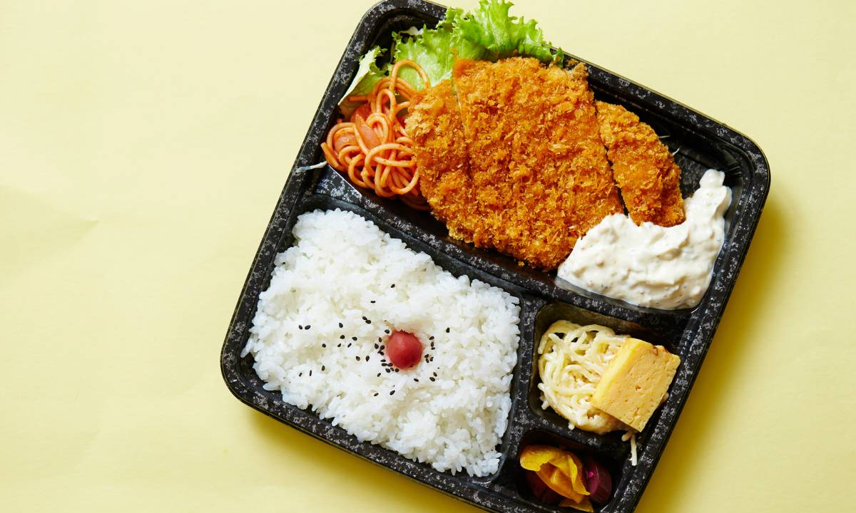 Bento box with fried pork cutlet (tonkatsu), rice, egg, and various vegetables