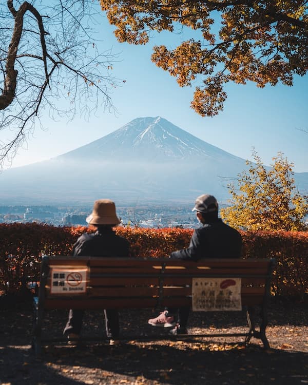 Two people sitting down on a bench, observing Mount Fuji in Tokyo