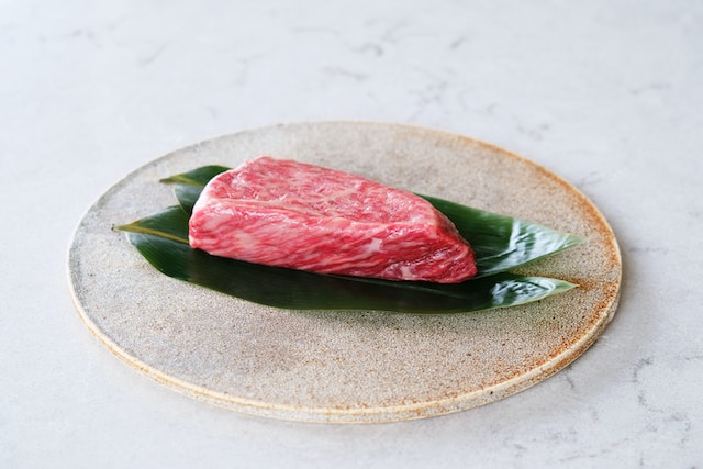 raw japanese steak set on two leaves over a plate