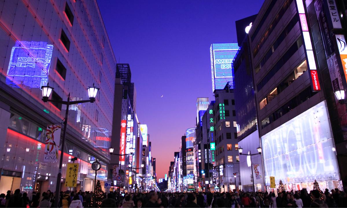 Japanese shopping district Ginza at night with crowded streets and bright lights