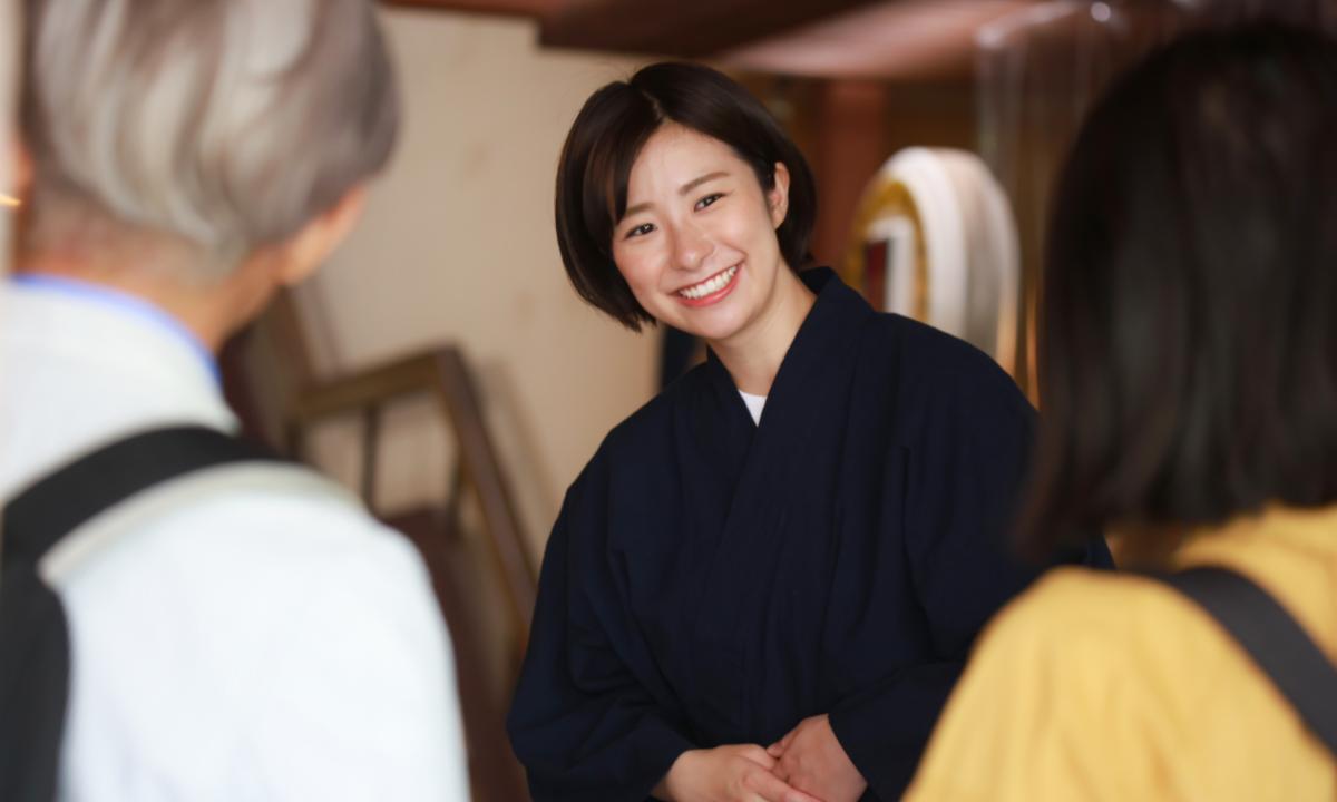 Japanese woman wearing kimono and welcoming guests to a Tokyo ryokan