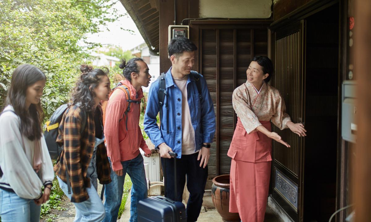 Japanese woman greeting guests at the entrance of a ryokan inn