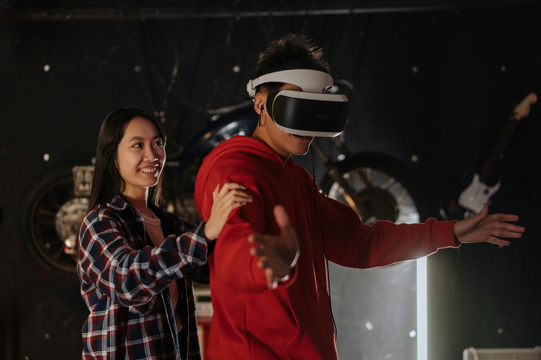A man using a VR headset with a girl who is not. They seem to engaged in some kind of game where the girl must guide him since his eyes are covered by the headset