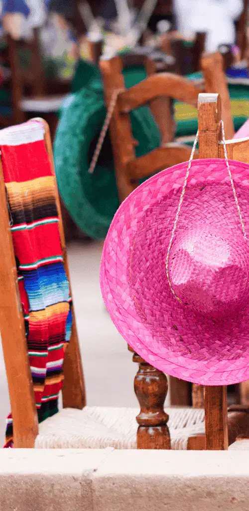 An image inside the best Mexican food in Tokyo restaurant with a pink hat and a colorful cloth hanging on the chairs.