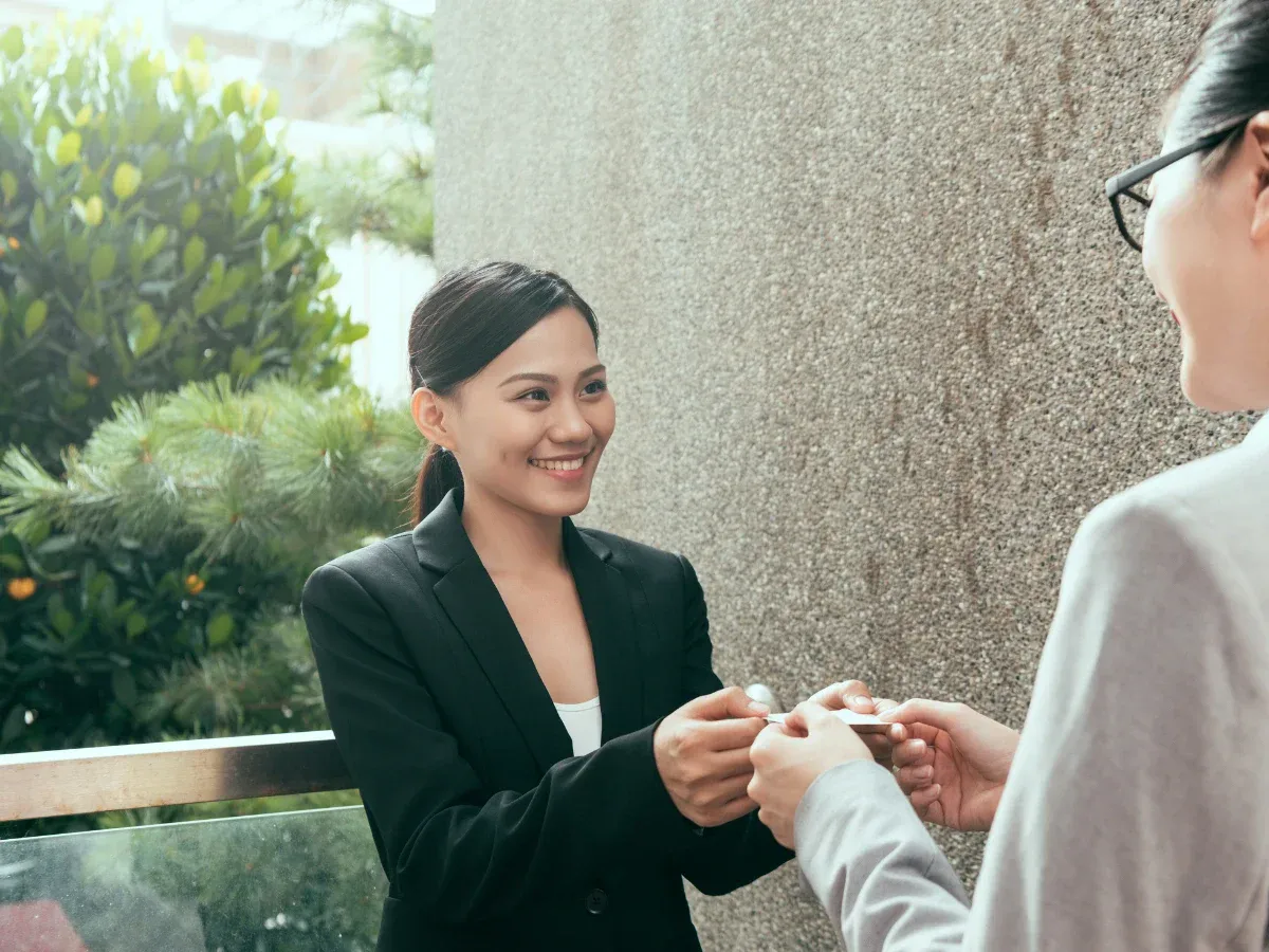 two women exchanging japanese business card using both hands