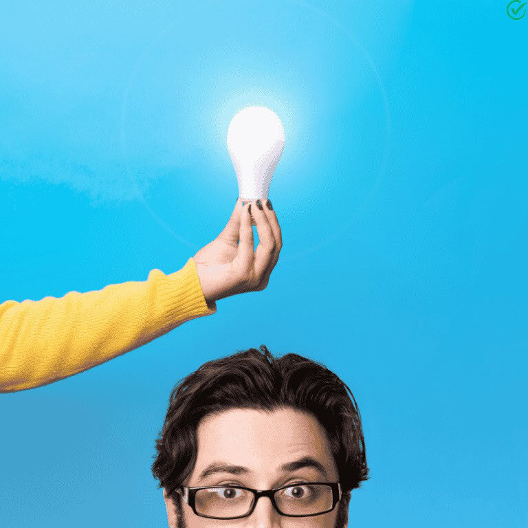 A guy in eyeglasses with a lightbulb on top of his head being held by a person in yellow sweater and a blue background.