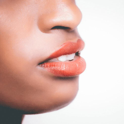 A close-up image of a woman in a side view of her face from nose to chin wearing a bold shade lipstick